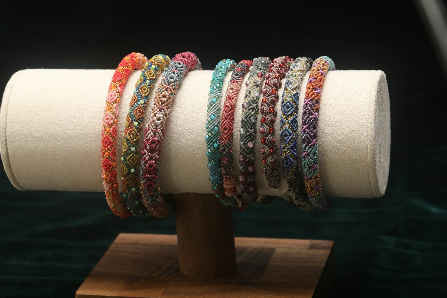 Braccialetti finemente lavorati con perline su un espositore cilindrico di velluto.